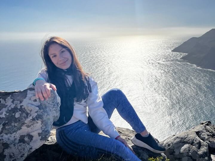A Tilting Futures gap year travel program student sitting at the edge of a cliff overlooking the sea