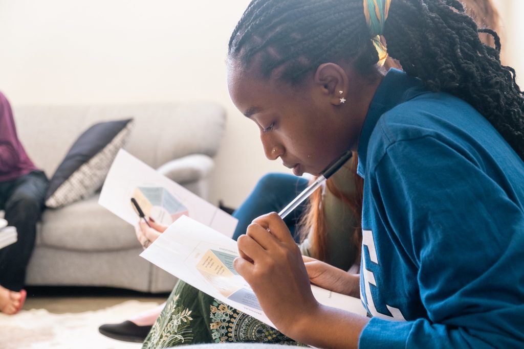 Student carefully reviewing study materials and taking notes, demonstrating focused preparation and independent learning skills before college.